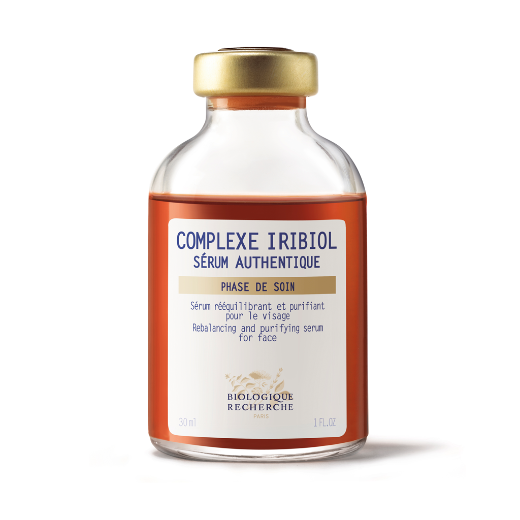 Skincare serum bottle with gold cap and white label on a white background